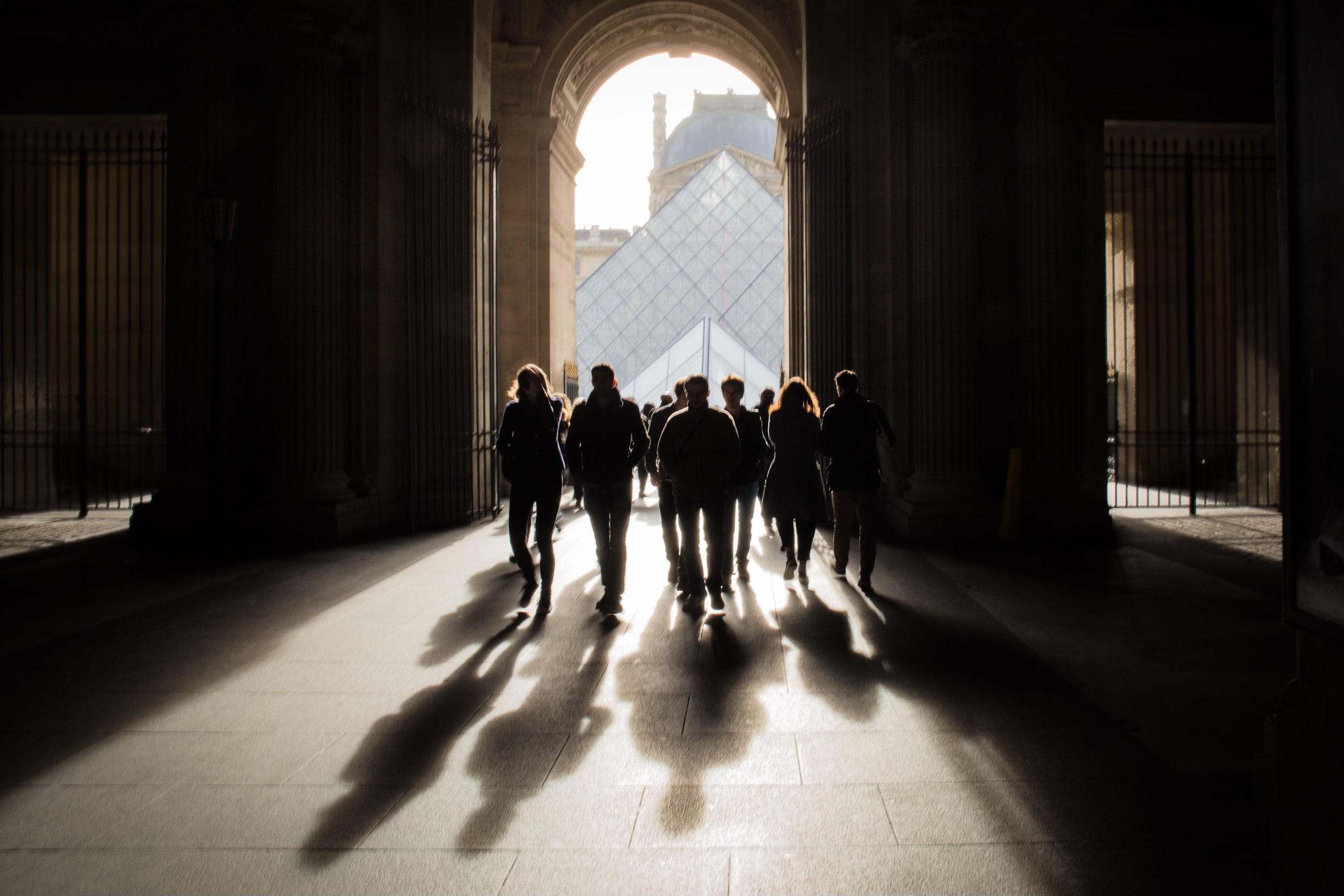 Walking through an archway towards the Louvre